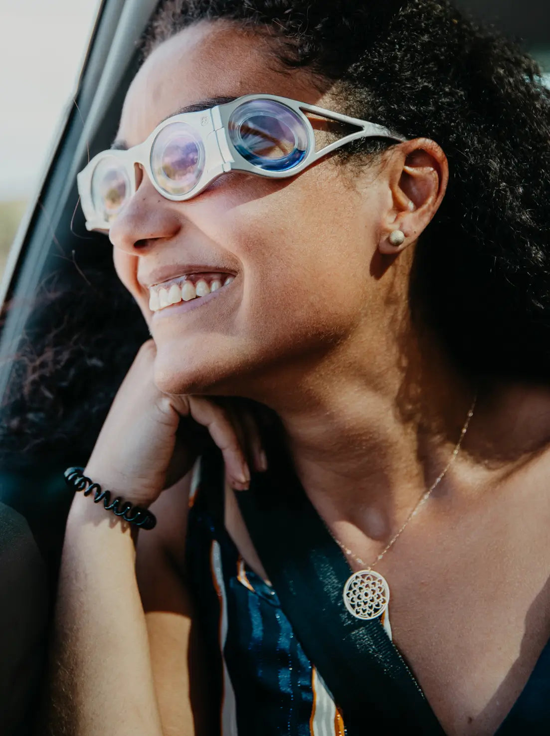 femme métisse en gros plan dans une voiture qui sourit avec des lunettes contre le mal des transports