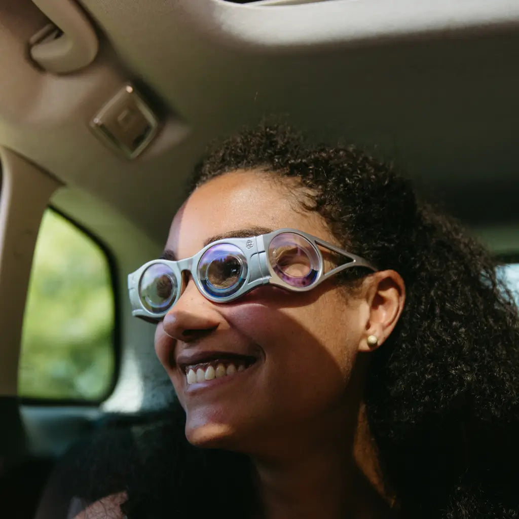 femme métisse en gros plan dans une voiture qui sourit avec des lunettes contre le mal des transports
