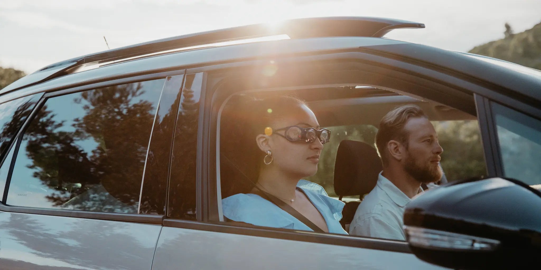 un homme et une femme dans une voiture qui roulent en pleine nature