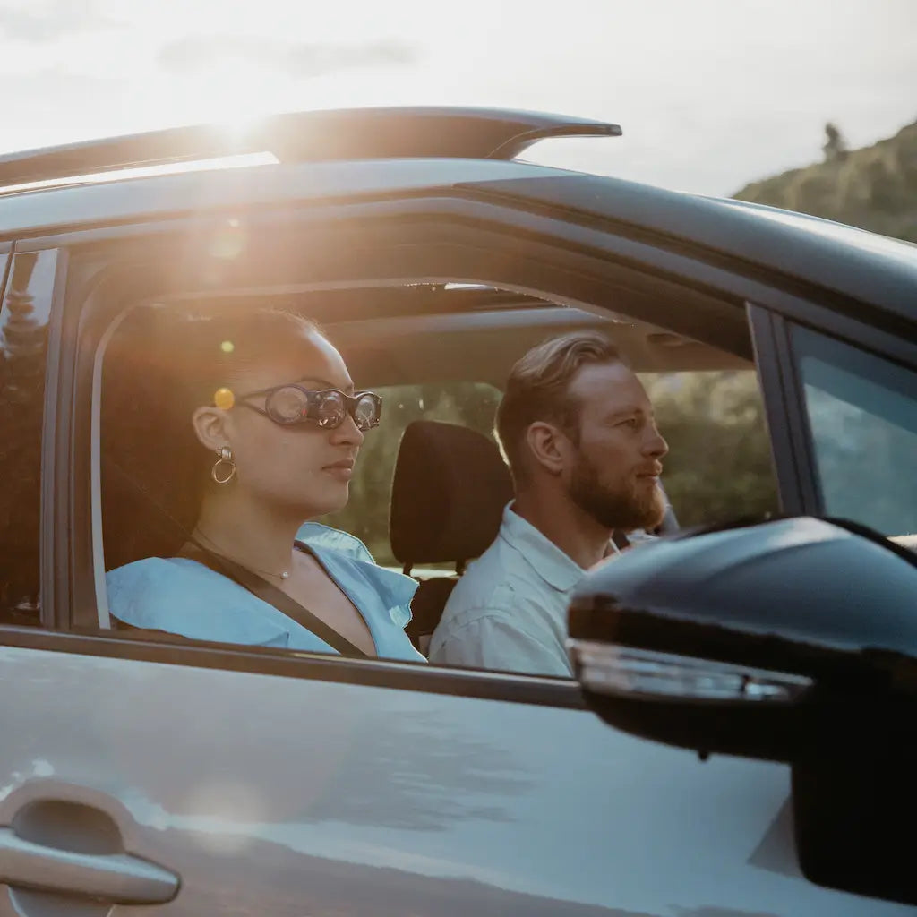 un homme et une femme dans une voiture qui roulent en pleine nature