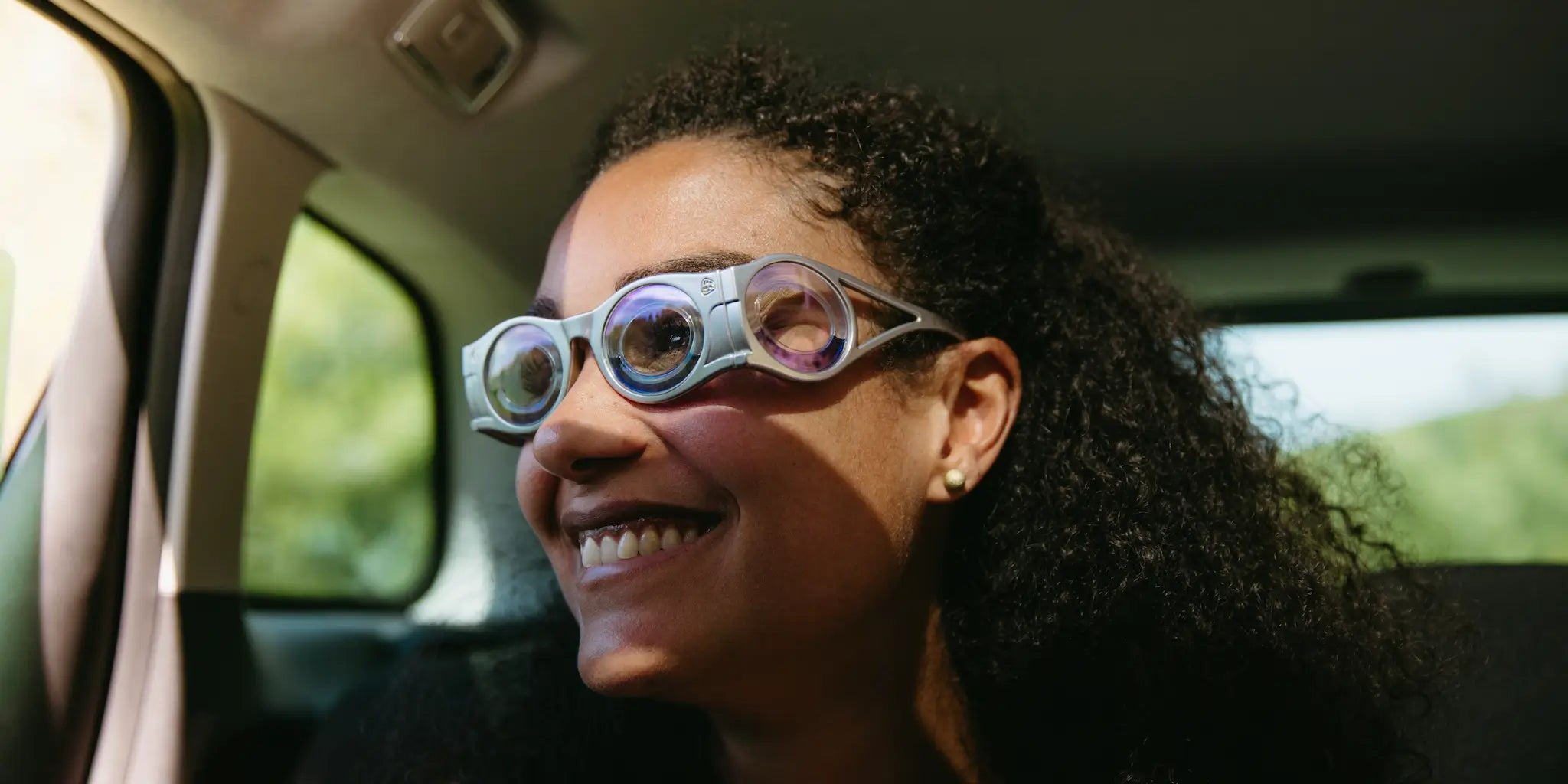 femme métisse en gros plan dans une voiture qui sourit avec des lunettes contre le mal des transports